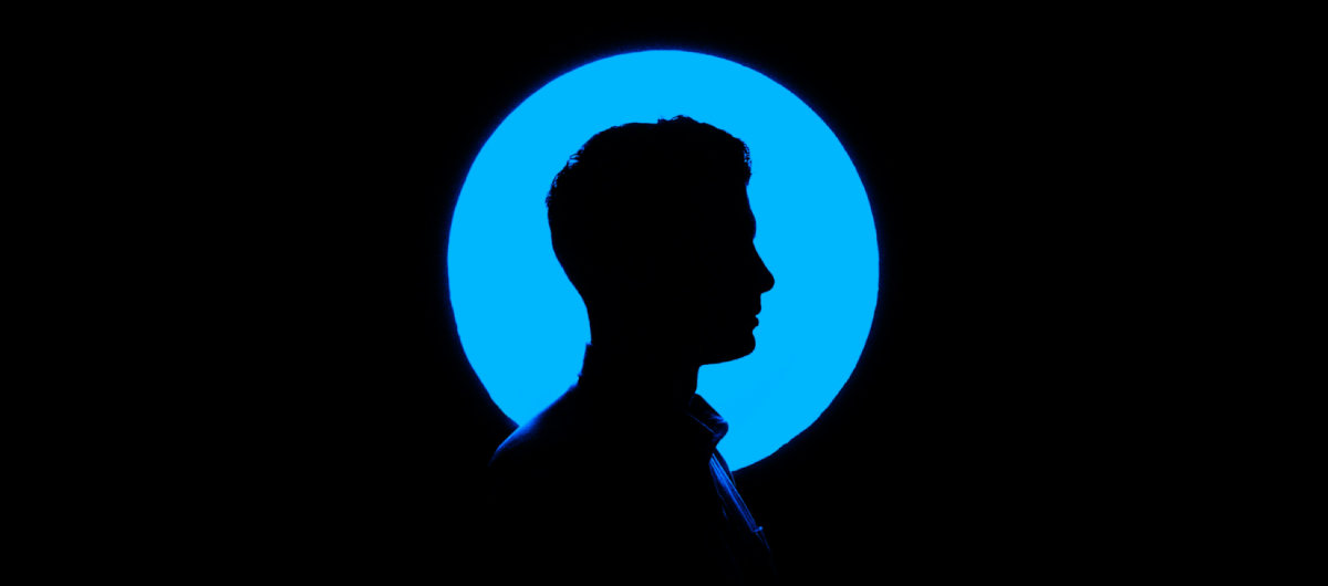 Silhouette eines Mannes im Profil vor leuchtend blauem Kreis